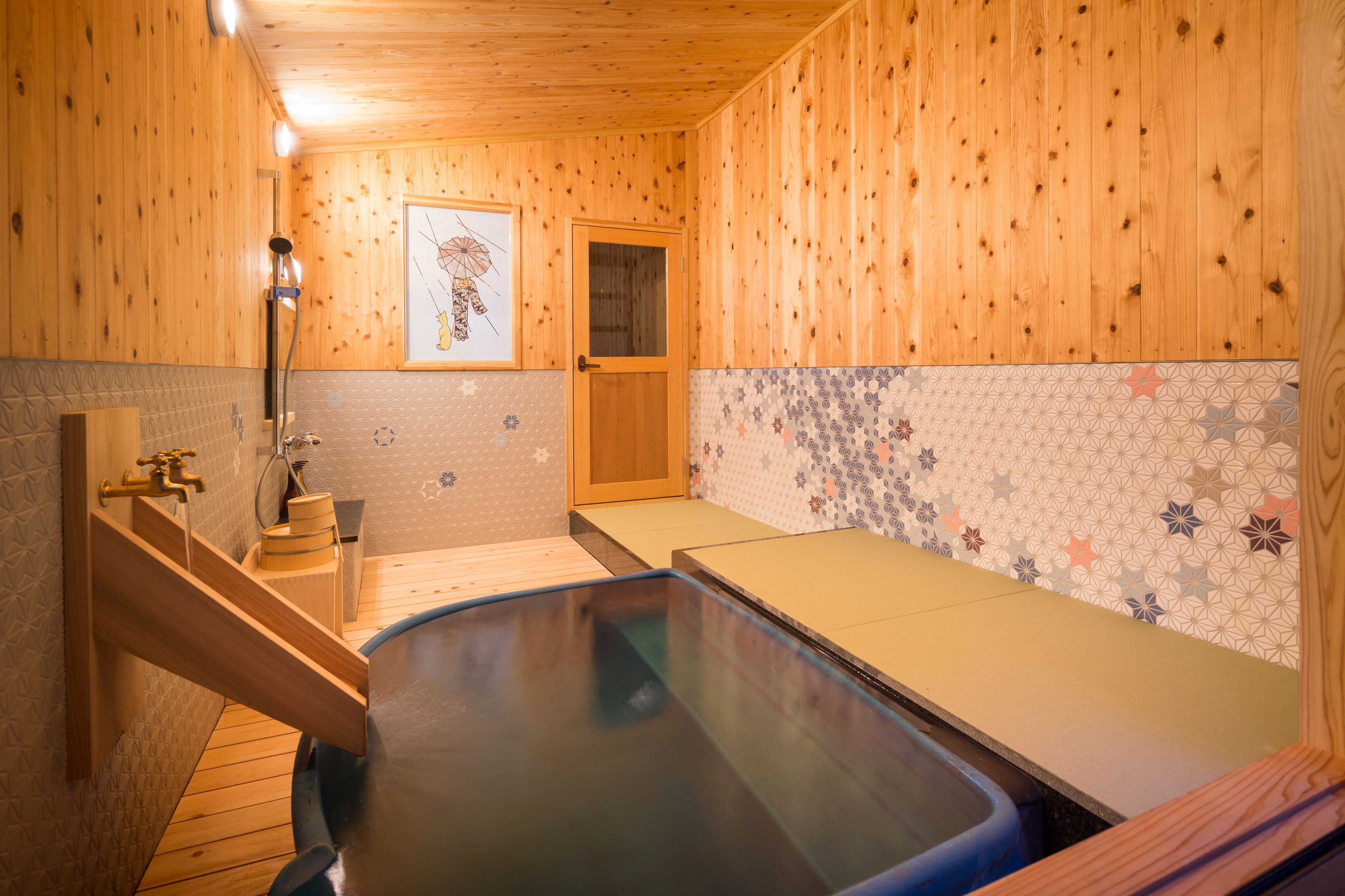 A wooden interior with a hot tub, a wooden door, and a tiled wall with a geometric pattern.