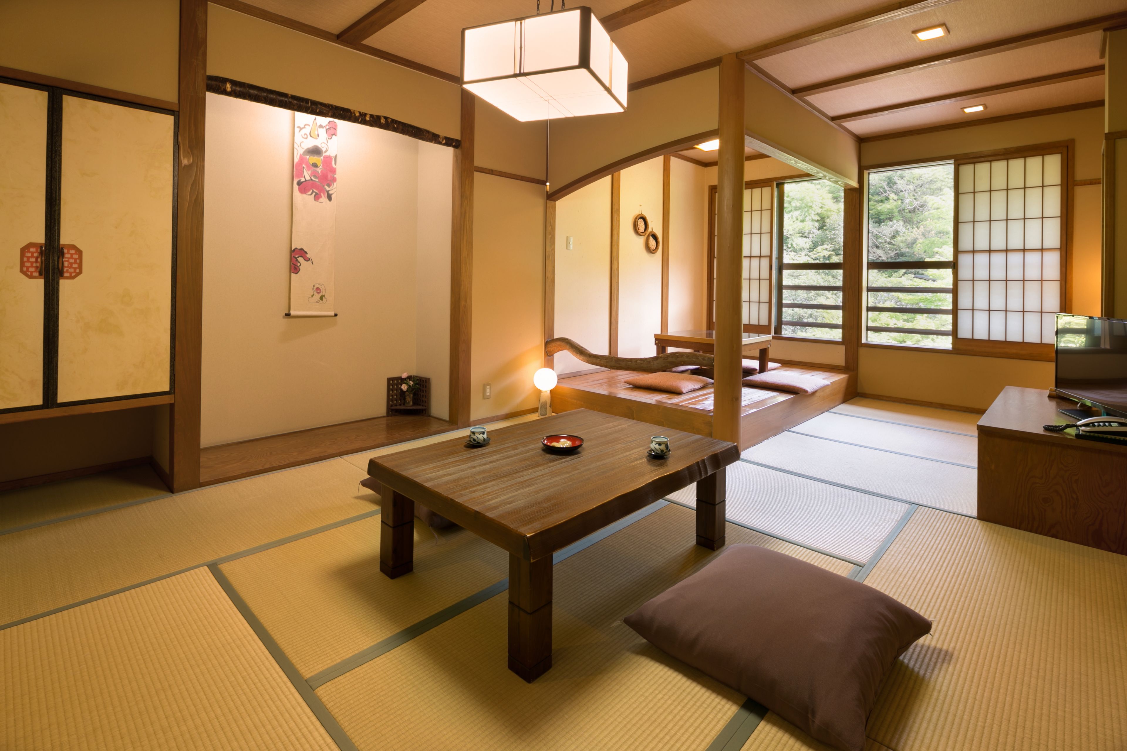 A traditional Japanese room with tatami flooring, a low wooden table, a pillow, and sliding doors.