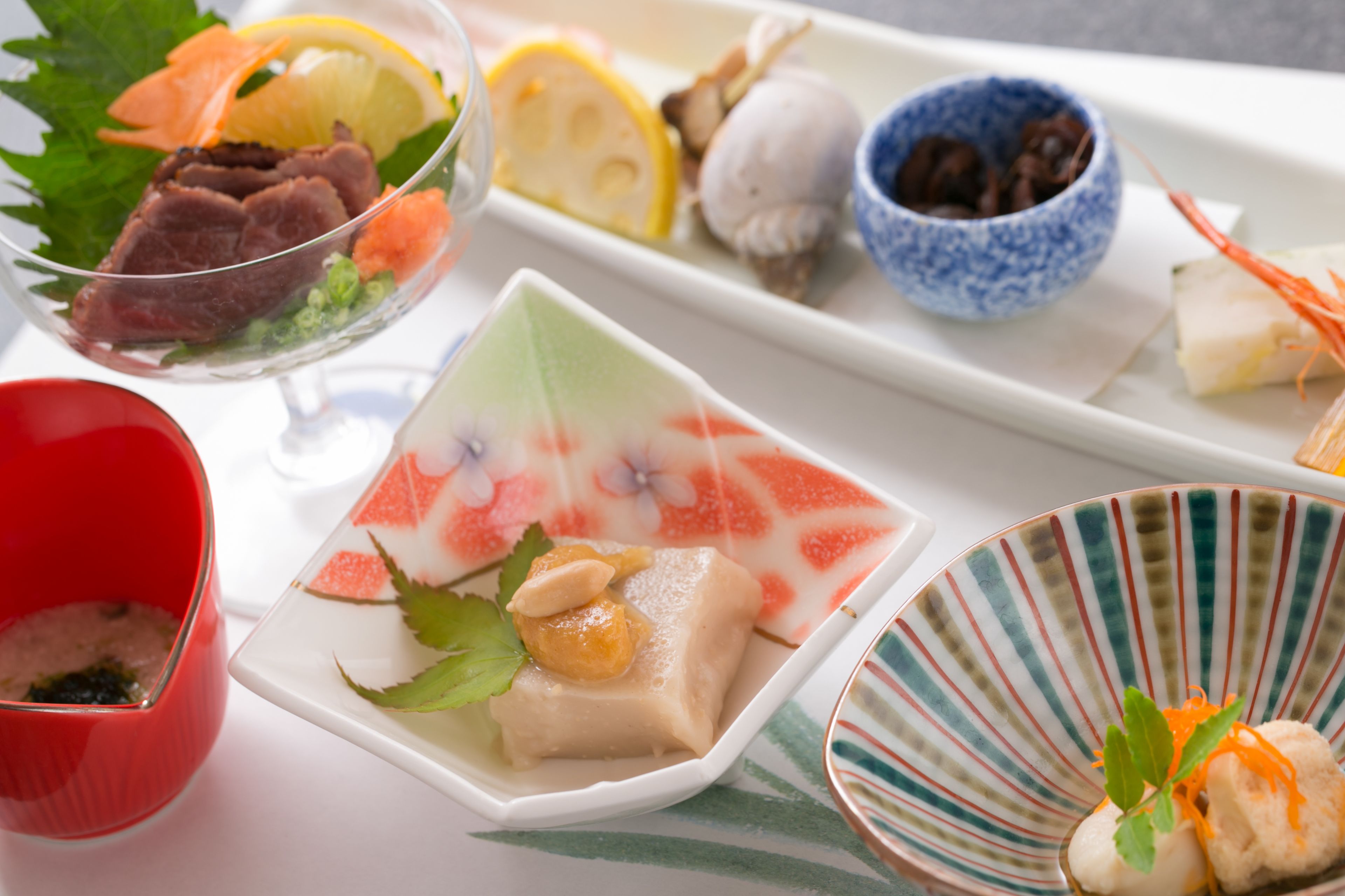 A variety of dishes on a tray, including a bowl of soup, a plate with a dessert, and several small dishes with different food items.