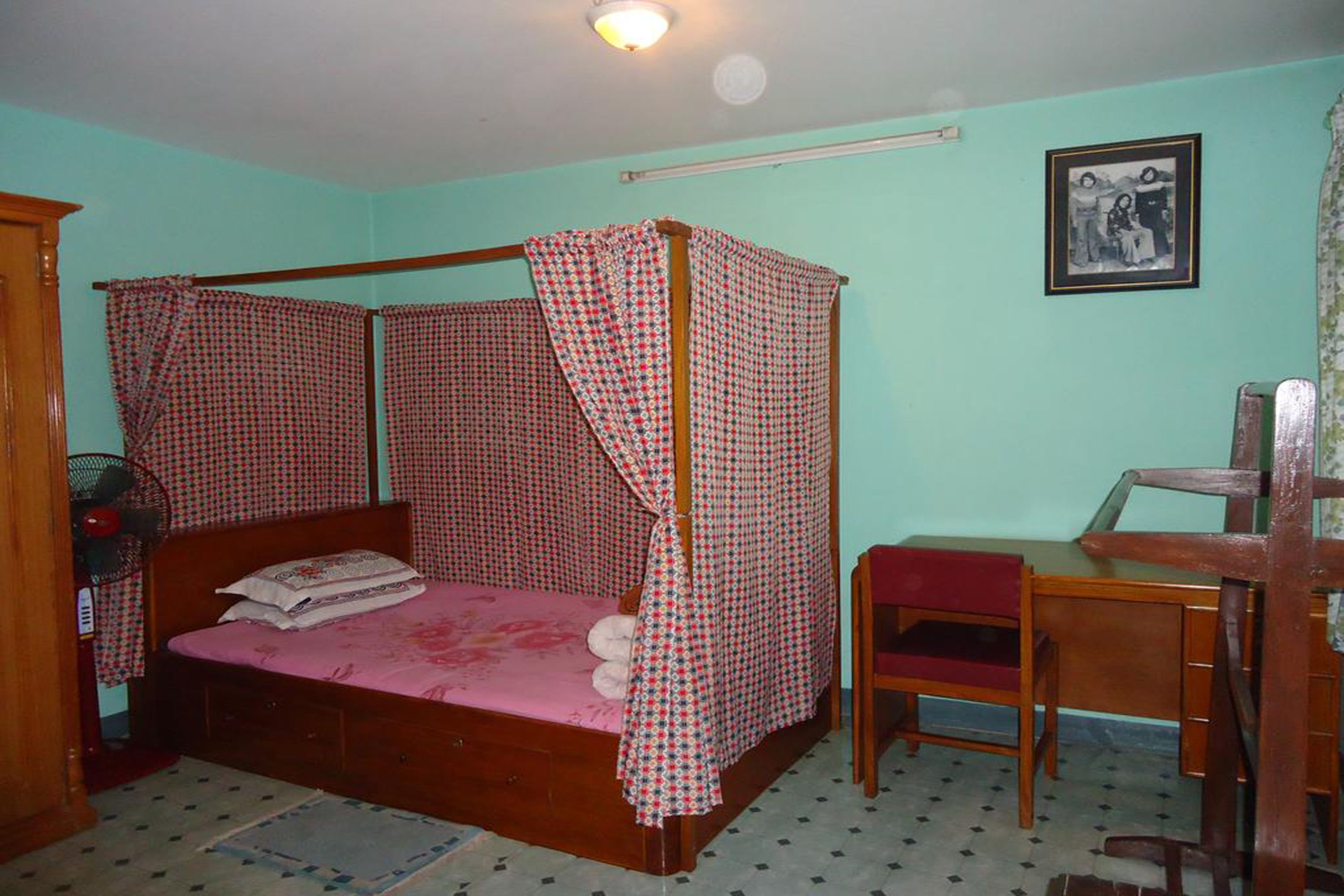 A bedroom with a four-poster bed, a desk, and a chair.