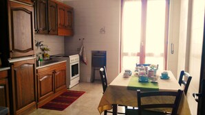 Une cuisine avec des meubles en bois, une cuisinière et un coin repas avec une table mise pour deux personnes.
