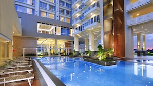 A modern hotel interior with a large indoor swimming pool, multiple balconies, and a well-lit atrium. - Aston Batam Hotel & Residence (Batam)