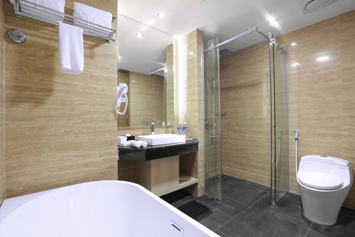 A modern bathroom with a glass-enclosed shower, a white bathtub, and a vanity with a sink and mirror.