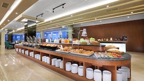 A buffet area with various food items and a counter with plates and utensils. - Aston Batam Hotel & Residence (Batam)