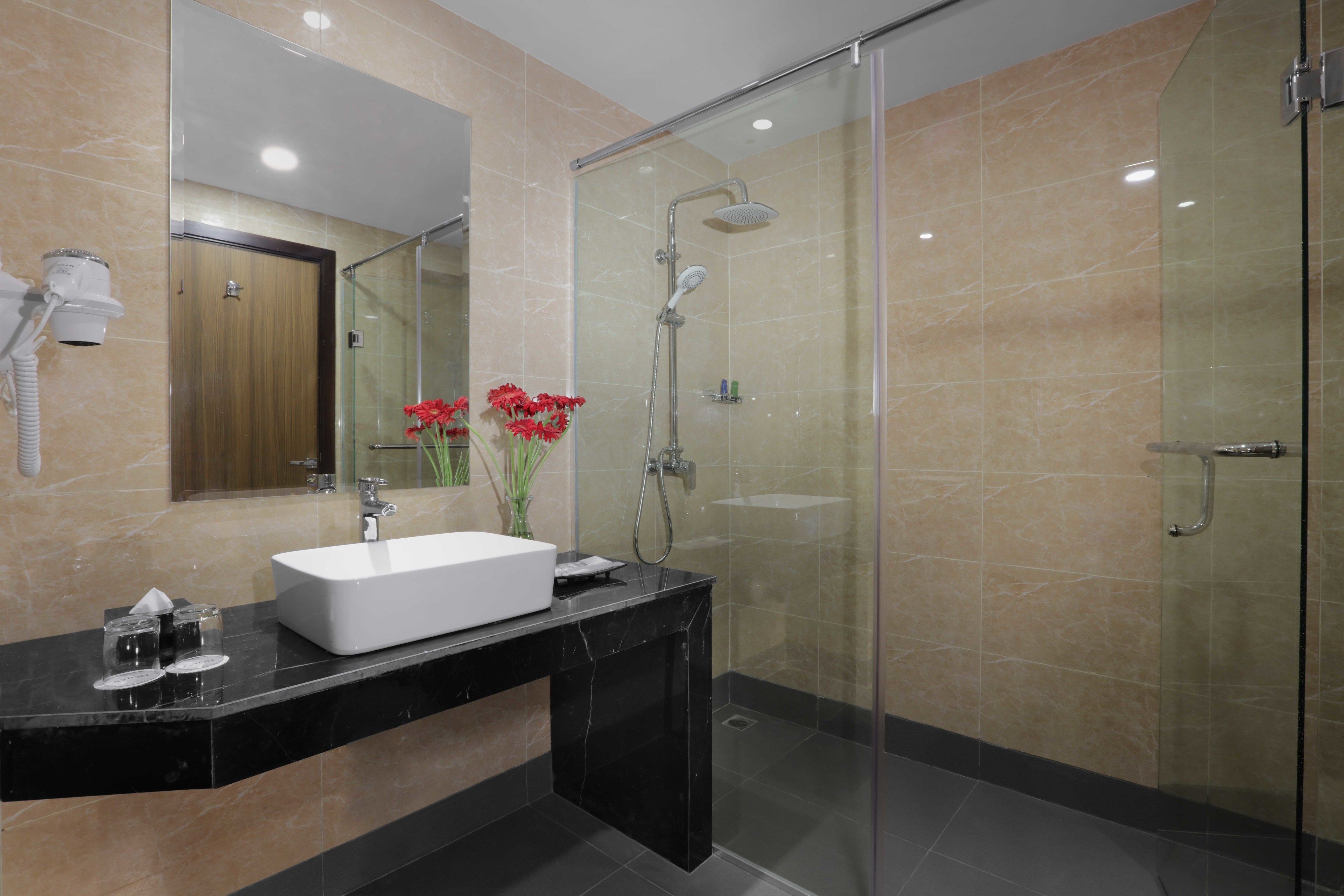 A modern bathroom with a glass shower enclosure, a white sink, and a mirror.