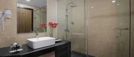 A modern bathroom with a glass shower enclosure, a white sink, and a mirror.