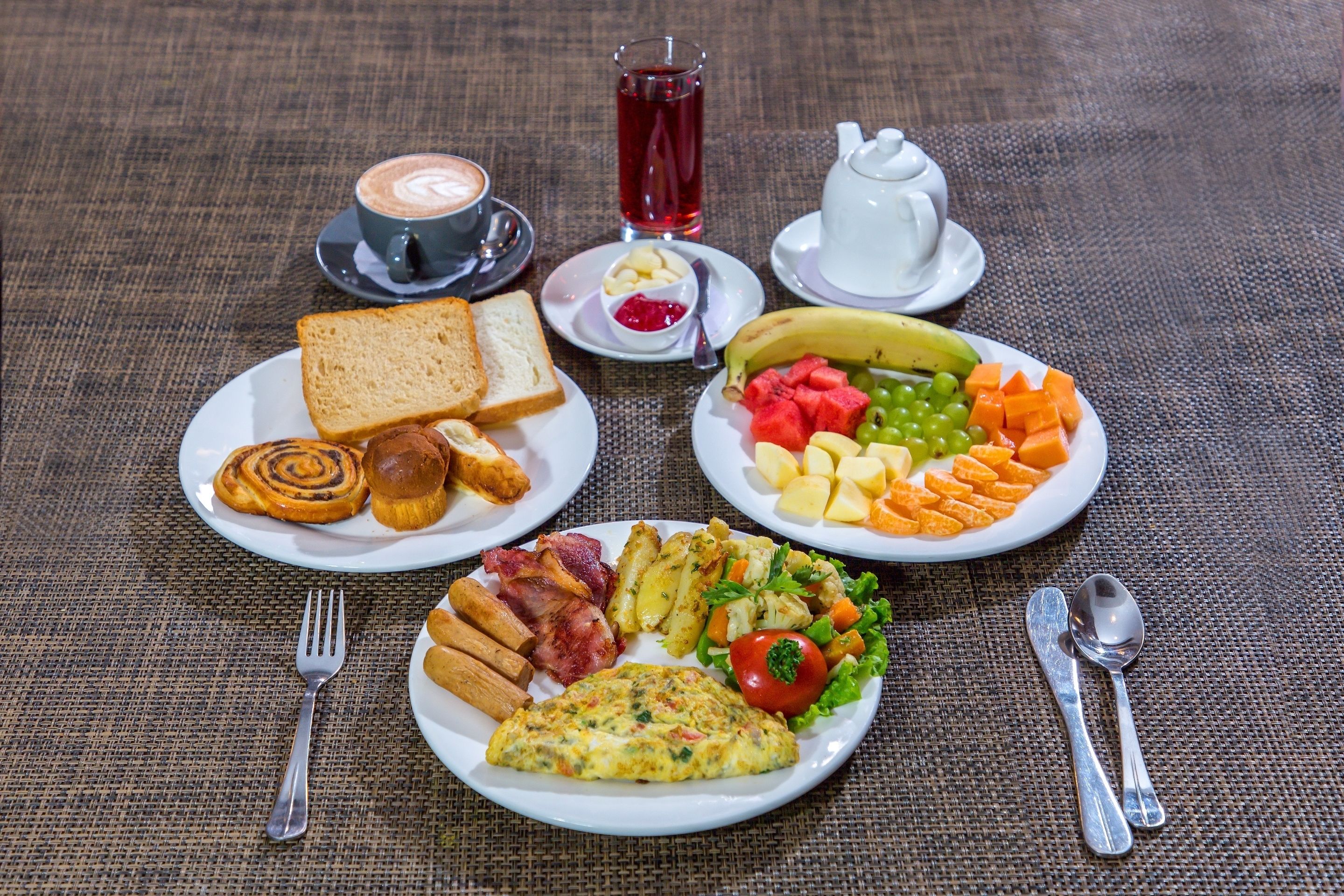 Desayuno con tostadas, huevos, tocino, papas y una variedad de frutas y verduras.