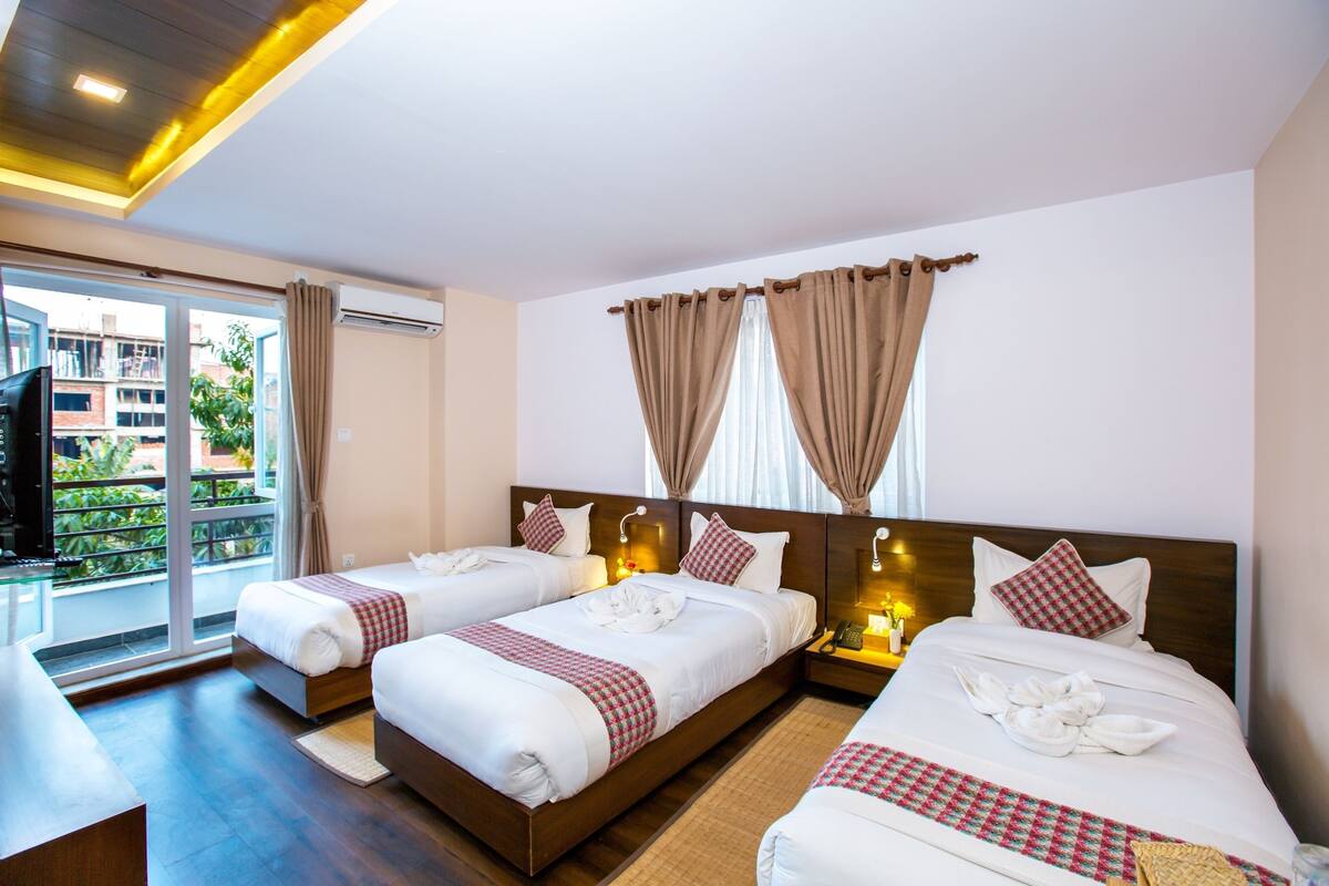 A hotel room with two beds, a TV, and a balcony with curtains.