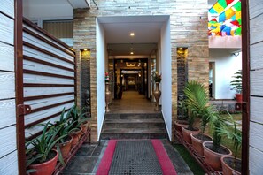 A hotel entrance with a stone facade, a staircase, and potted plants. - Kathmandu Suite Home (Kathmandu)