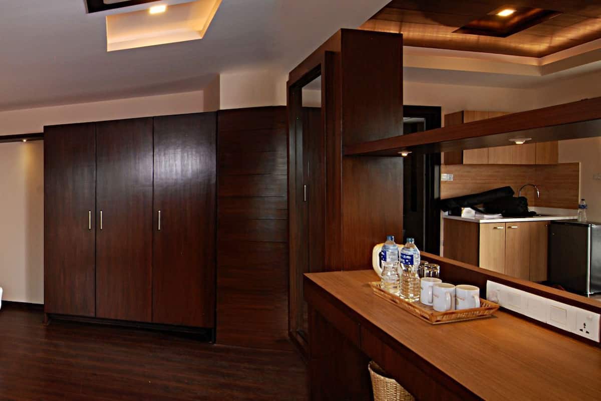 A hotel room with a large bed, a wardrobe, a desk with a tray of toiletries, and a mirror.