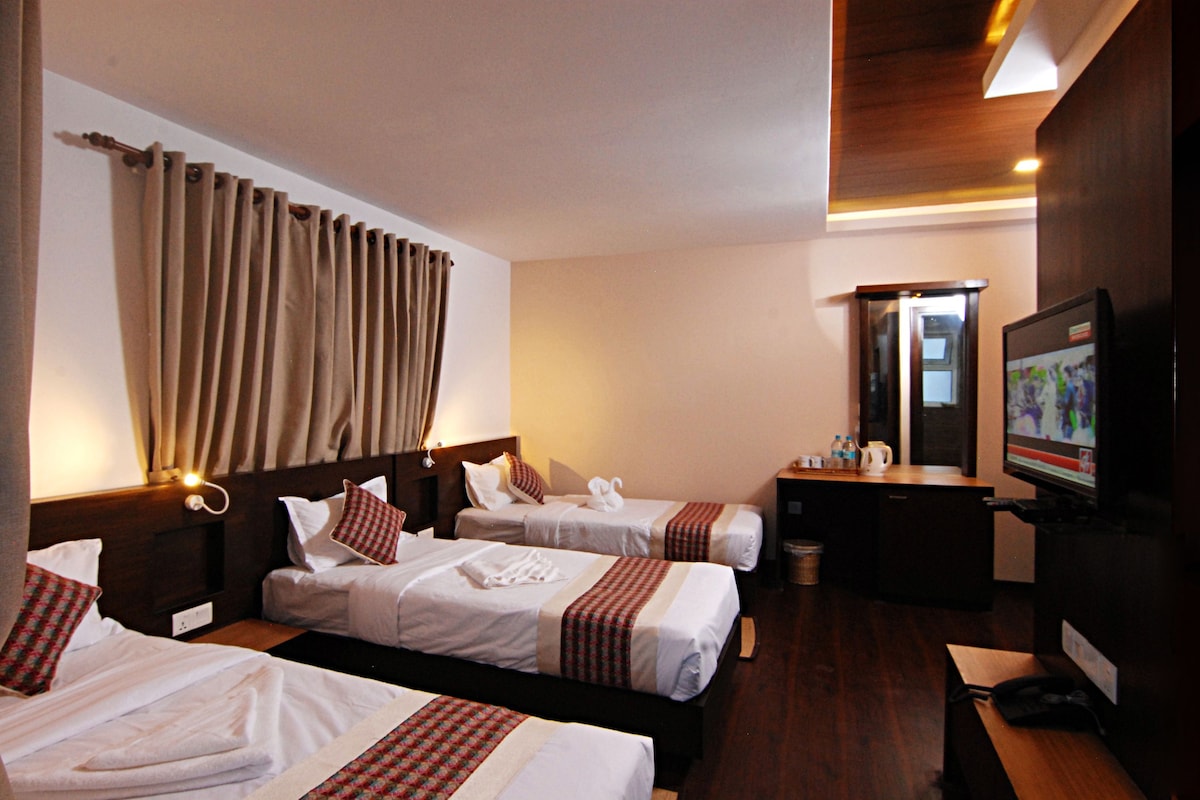 A hotel room with two beds, a television, a desk, and a mirror.