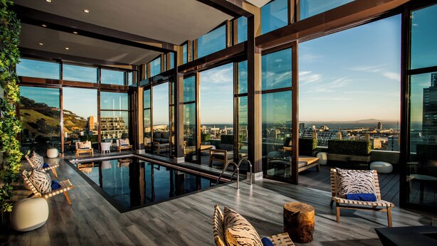 Un moderno bar en la azotea con piscina, amplias ventanas y vistas a la ciudad.