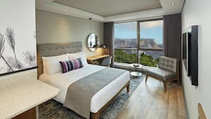 Una habitación de hotel moderna con una cama grande, un escritorio, una silla y vistas a la montaña.