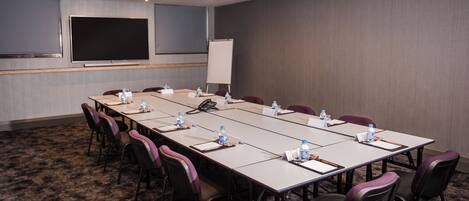 A conference room with a long table, chairs, water bottles, nameplates, and a whiteboard.