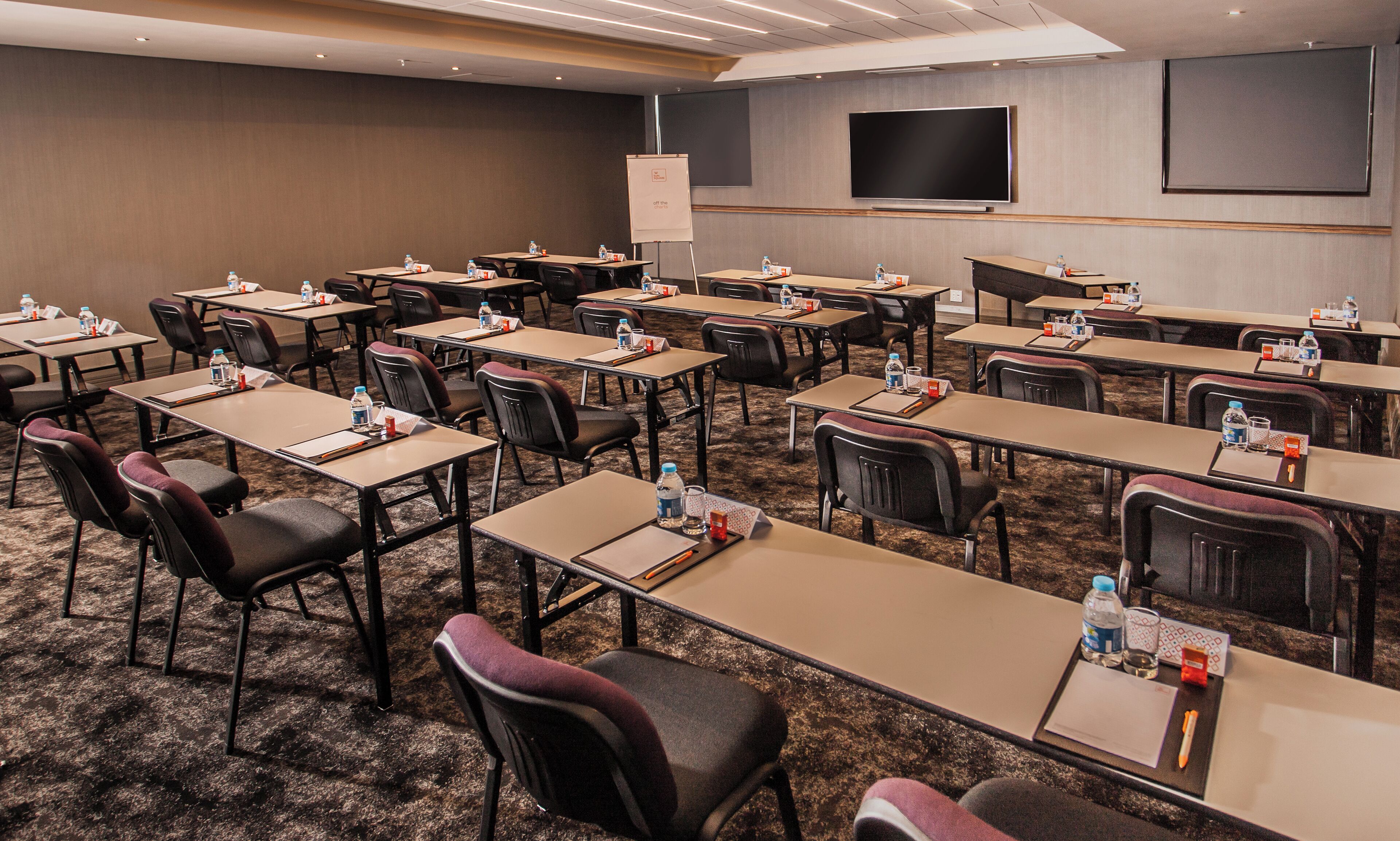A conference room with multiple tables and chairs, equipped with water bottles and nameplates.