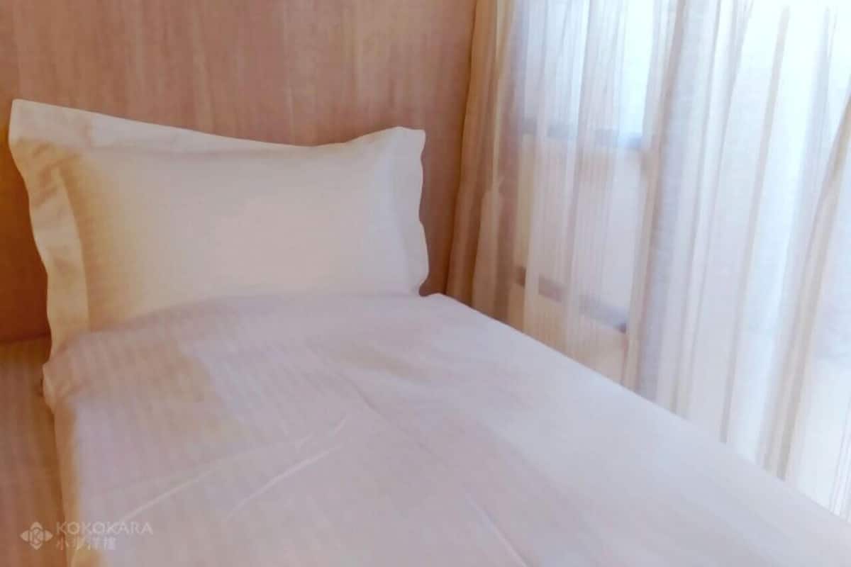 A bed with white bedding and sheer curtains.