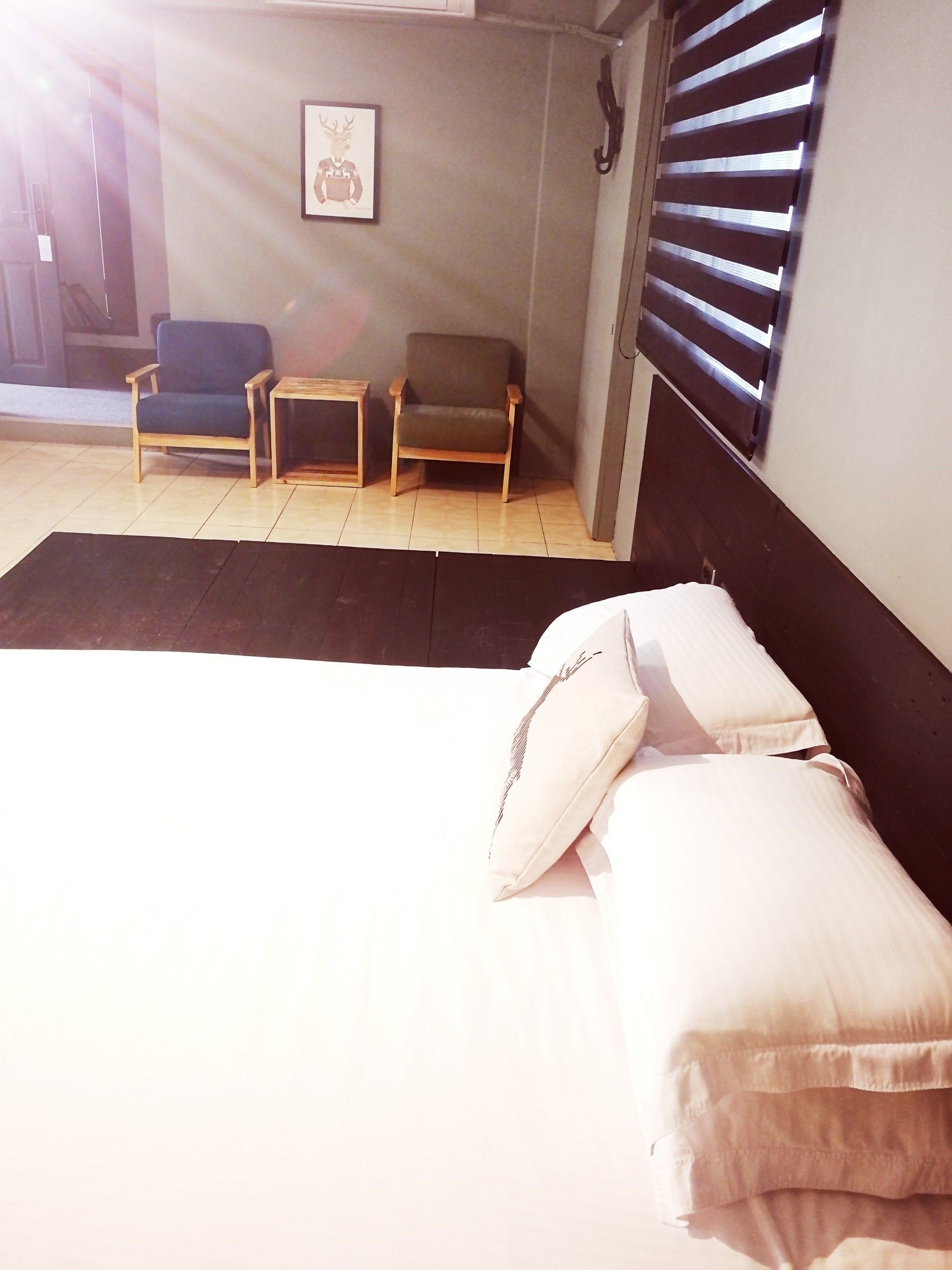 A bedroom with a bed, two chairs, a small table, and a picture on the wall.