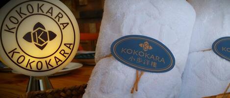 A display of towels with the Kokokara logo, placed on a woven mat.