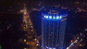 Ett högt hotell med upplysta skyltar och en framträdande, vertikal ljuslist.