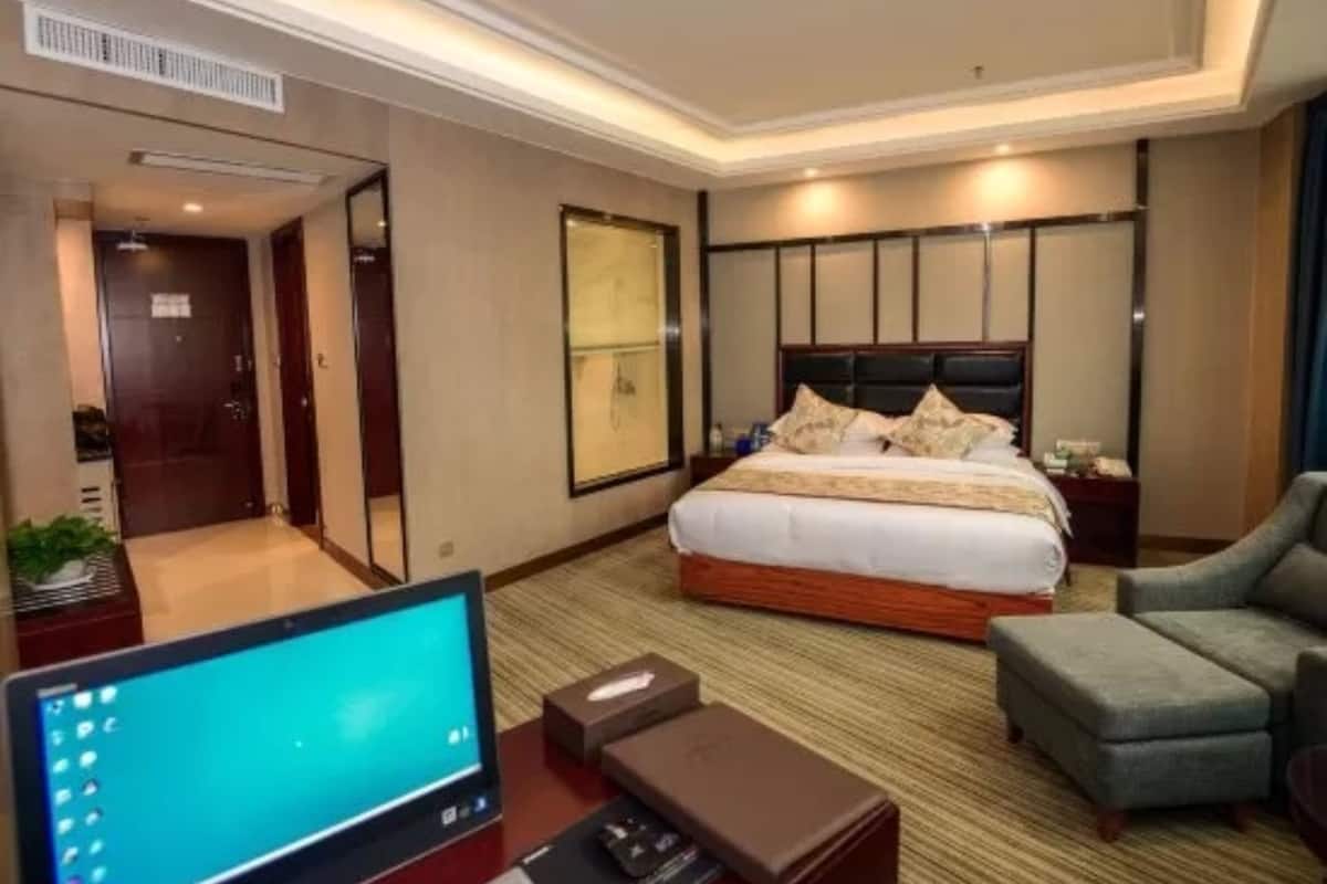 A hotel room with a large bed, a desk with a computer, a chair, and a TV.