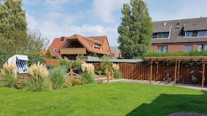 A residential area with a well-maintained lawn, a wooden deck, and a covered bike parking area.