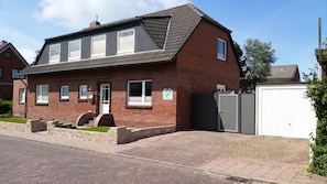 A two-story brick house with a sloped roof, a front door, and a garage.