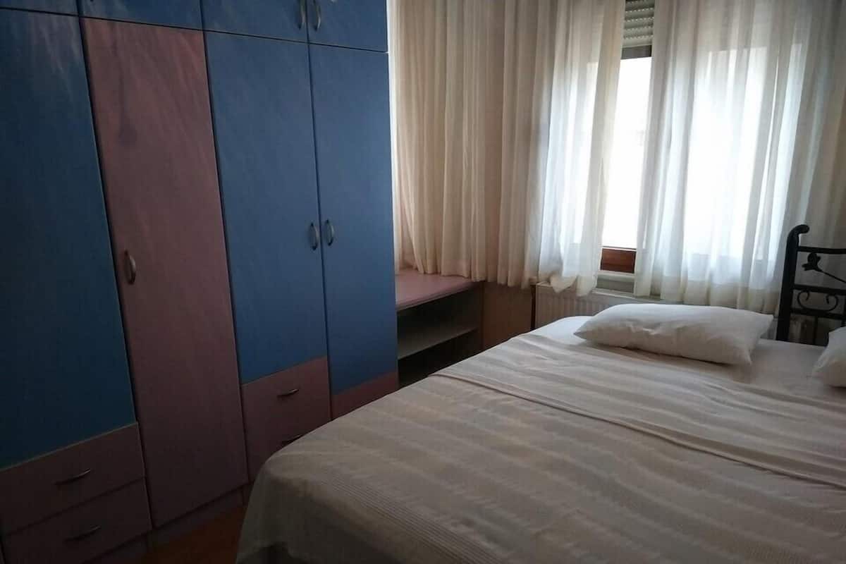 A bedroom with a bed, a wardrobe, and a window with curtains.
