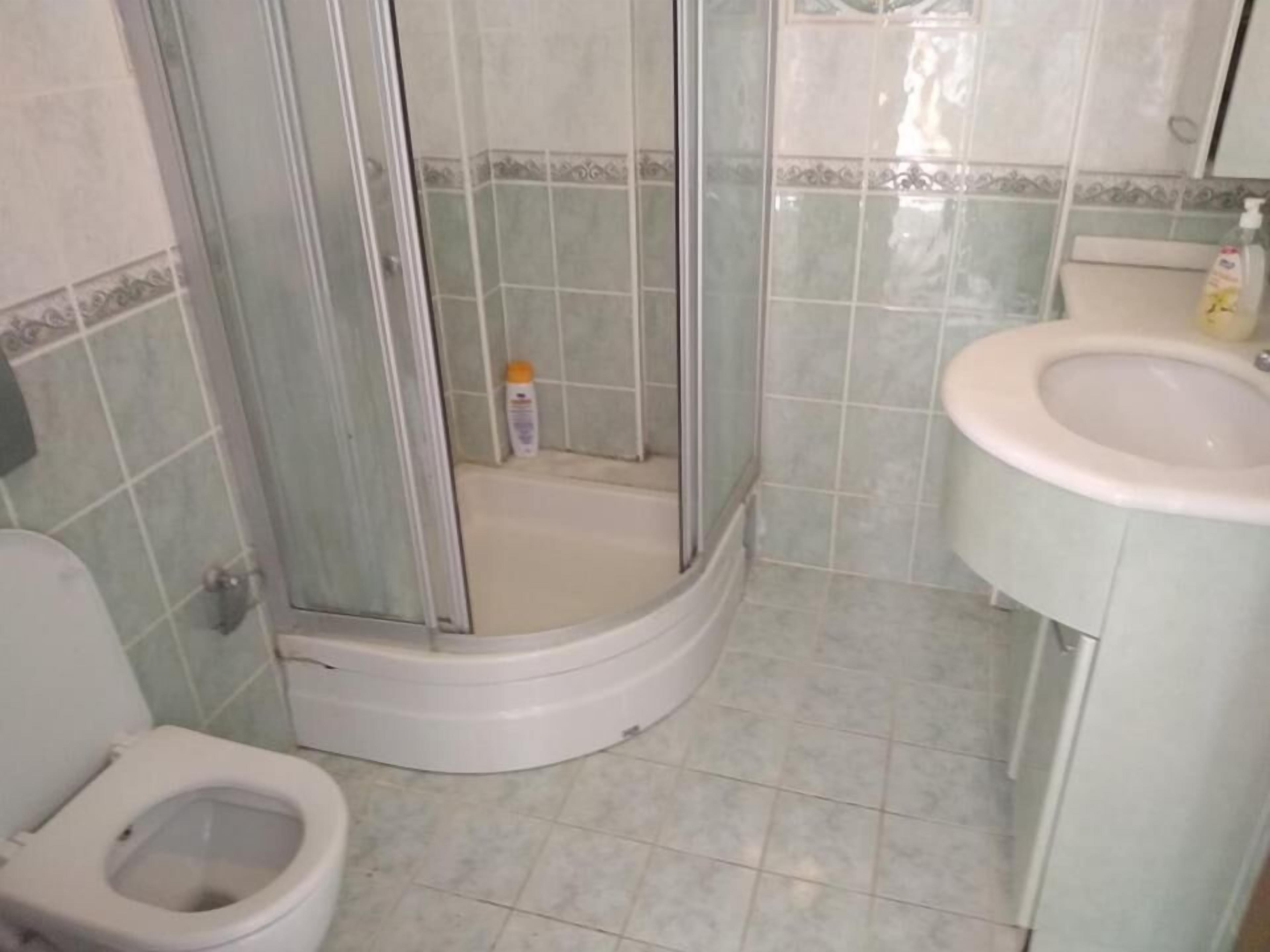 Un baño con inodoro, cabina de ducha y lavamanos.