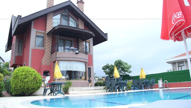 A two-story building with a pool area, outdoor seating, and a Coca-Cola branded umbrella. - Sile Dikcati Pansiyon (Sile)