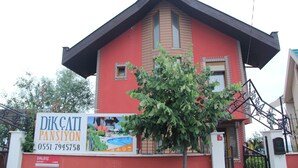 A red building with a signboard advertising a property named "DİKÇATI PANSİYON" with contact number "0551 7945758". - Sile Dikcati Pansiyon (Sile)