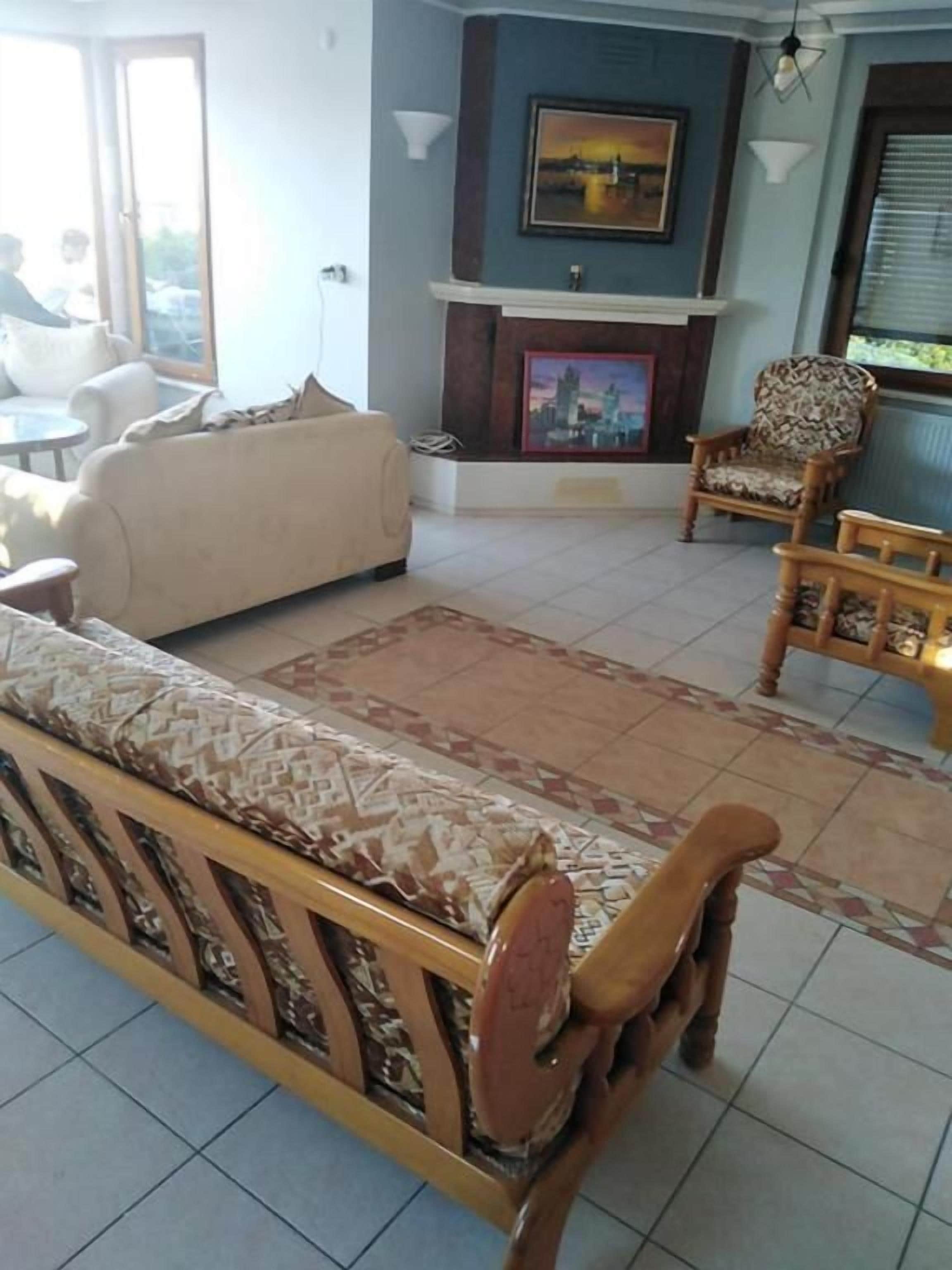 Una sala de estar con un sofá, sillones, un banco de madera, una chimenea y un cuadro con una vista urbana.