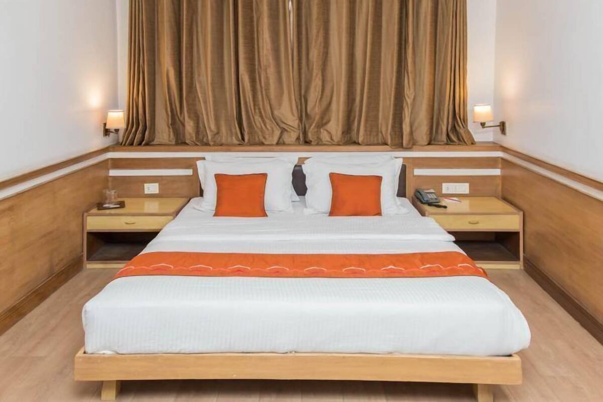 A hotel room with a wooden bed, two nightstands, a telephone, and a lamp on each side.