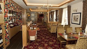 A hotel lobby with a wine cellar, a dining area with patterned chairs, and a chandelier.