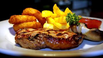 Un plato con carne a la parrilla, alimentos fritos y verduras.
