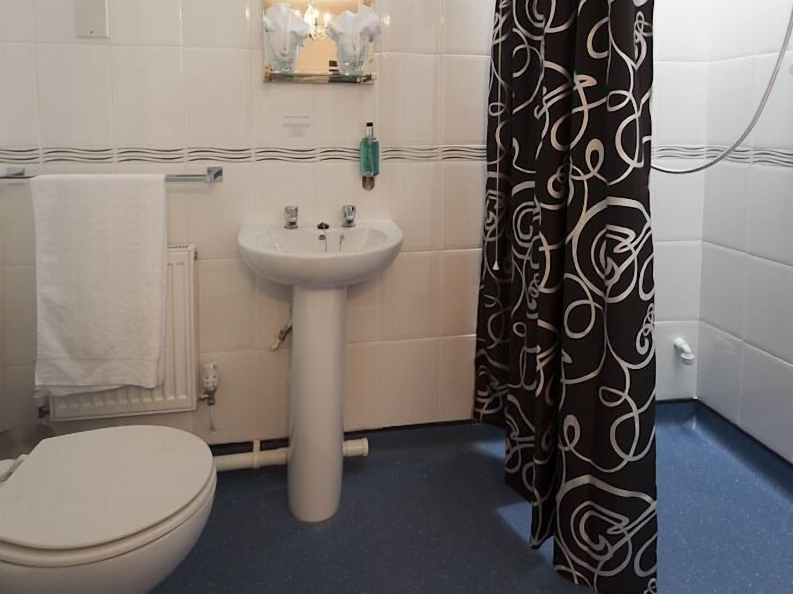 A bathroom with a white sink, a toilet, and a shower curtain with a black and white swirl pattern.