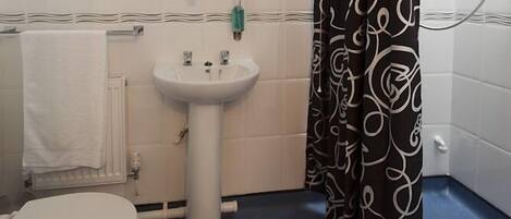 A bathroom with a white sink, a toilet, and a shower curtain with a black and white swirl pattern.