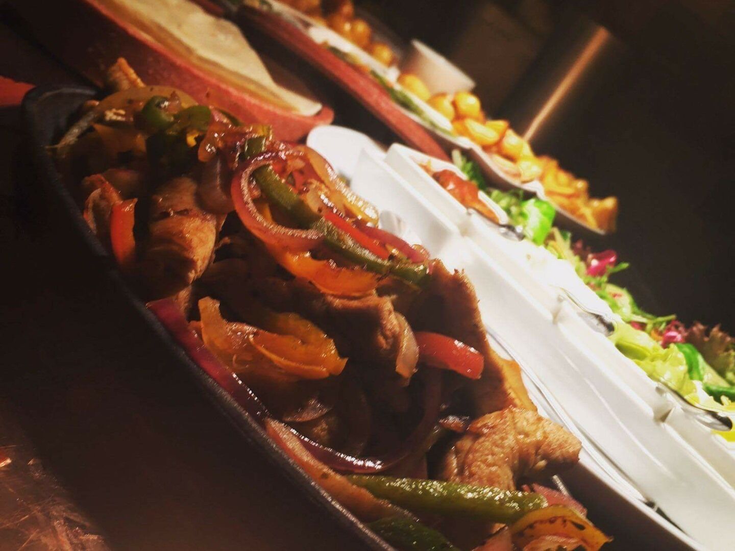 A buffet with various dishes including meat, vegetables, and salads.