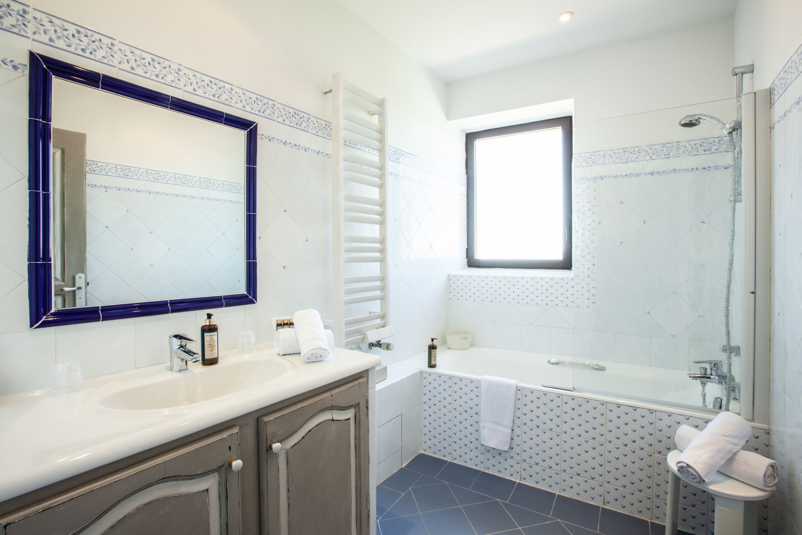 A bathroom with a large mirror, two sinks, a bathtub, and a shower.