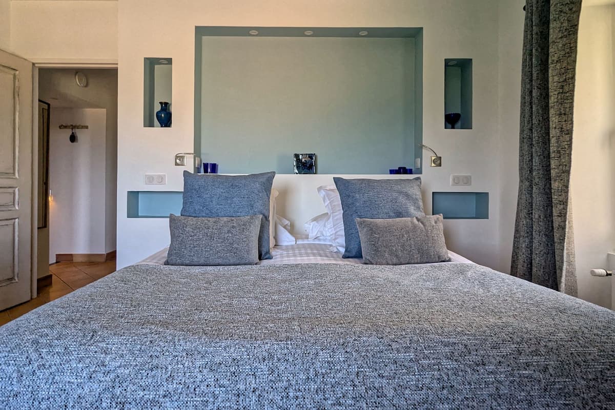 A bedroom with a large bed, two bedside tables, a mirror, and a door.