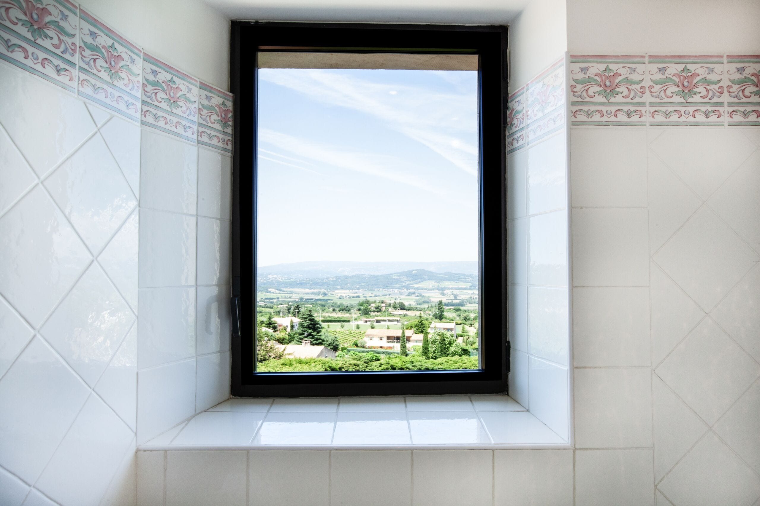A window with a view of a residential area and distant mountains.