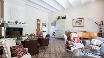 Un salon spacieux doté d’une cheminée, de sièges confortables, d’un piano et d’un meuble décoratif.