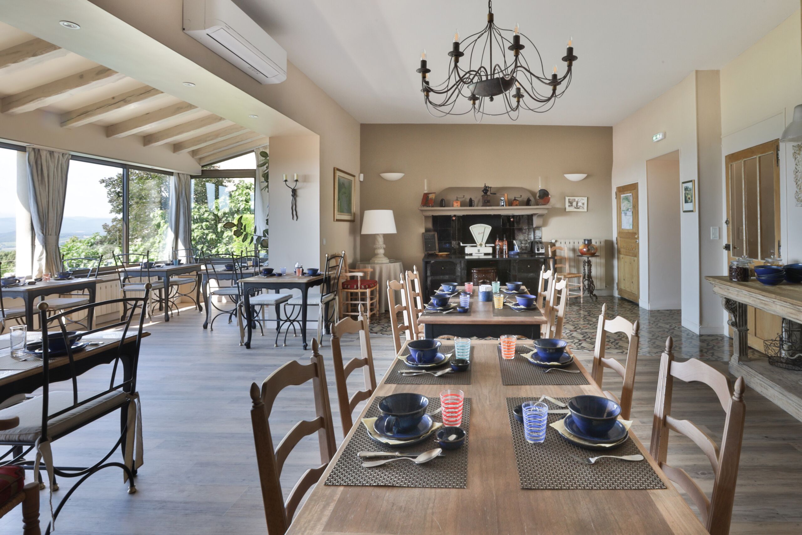 A spacious dining area with a long wooden table set for a meal, surrounded by wooden chairs.