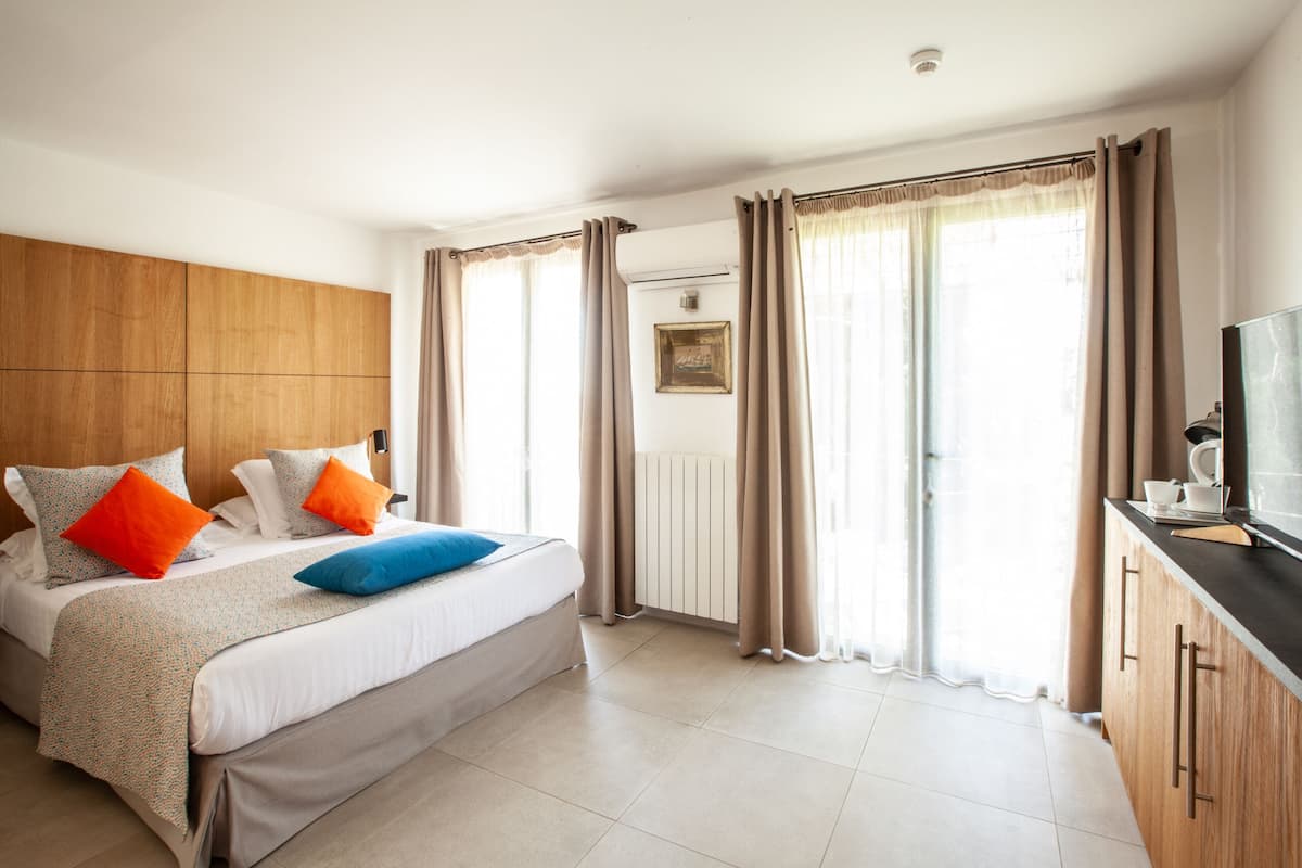 A hotel room with a bed, curtains, a television, and a radiator.