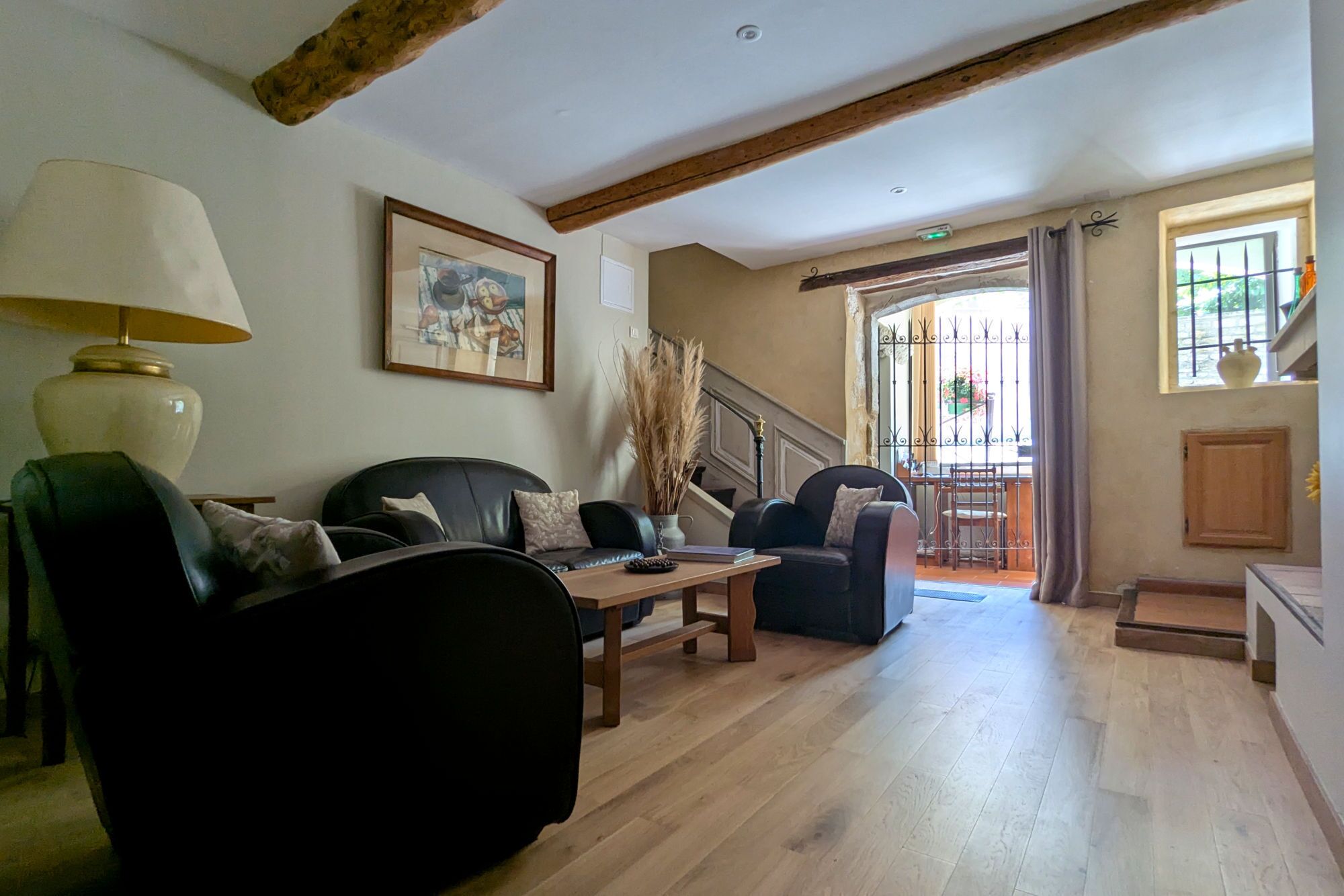 Uma sala de estar espaçosa com piso de madeira, um sofá, uma mesa de centro e uma luminária. Há uma escada que leva a uma varanda com vista.