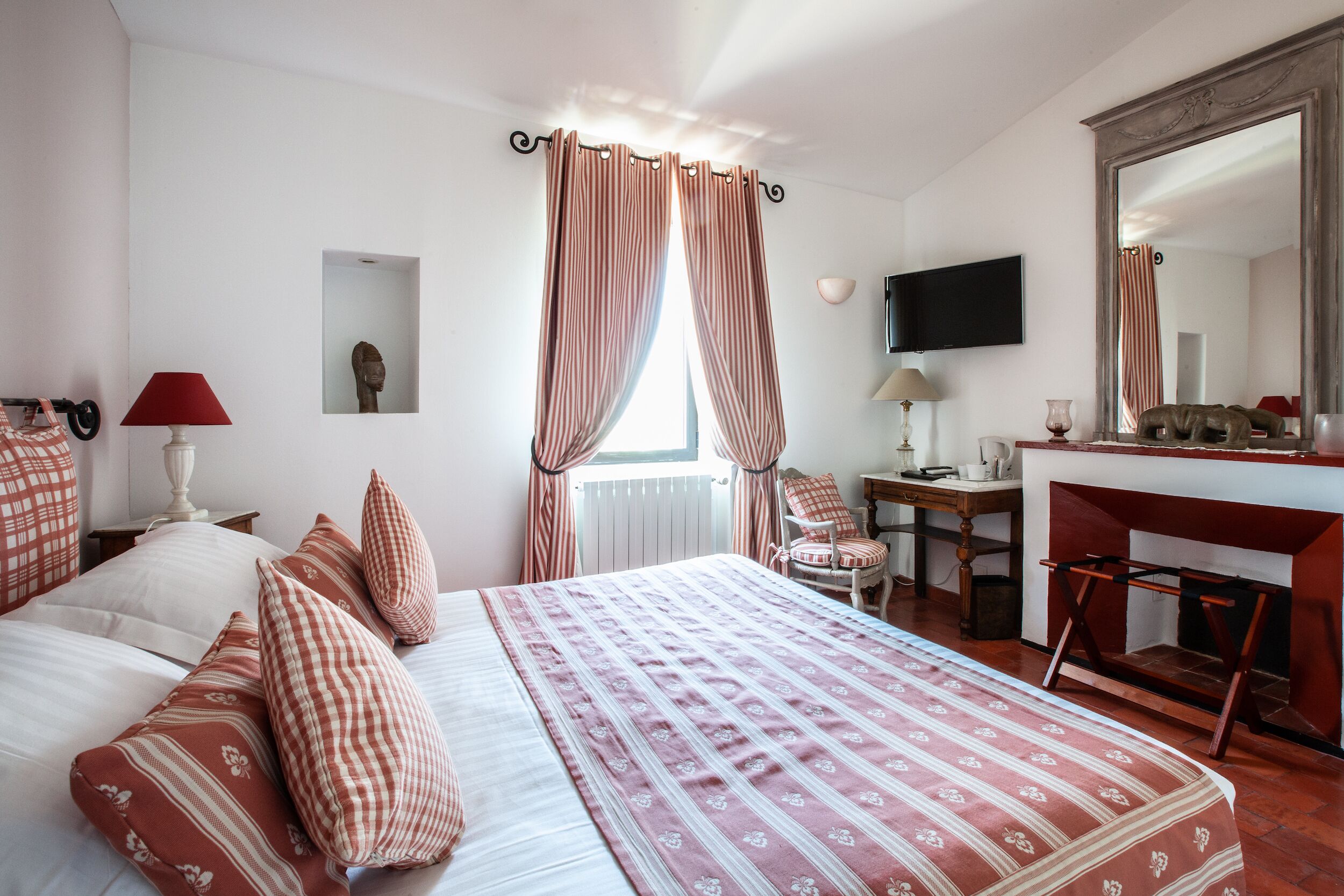 A bedroom with a bed, a desk, a chair, a TV, and a mirror.