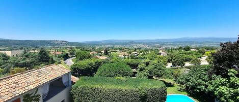 Zona residencial con piscina, césped verde y casas con tejados de tejas rojas.