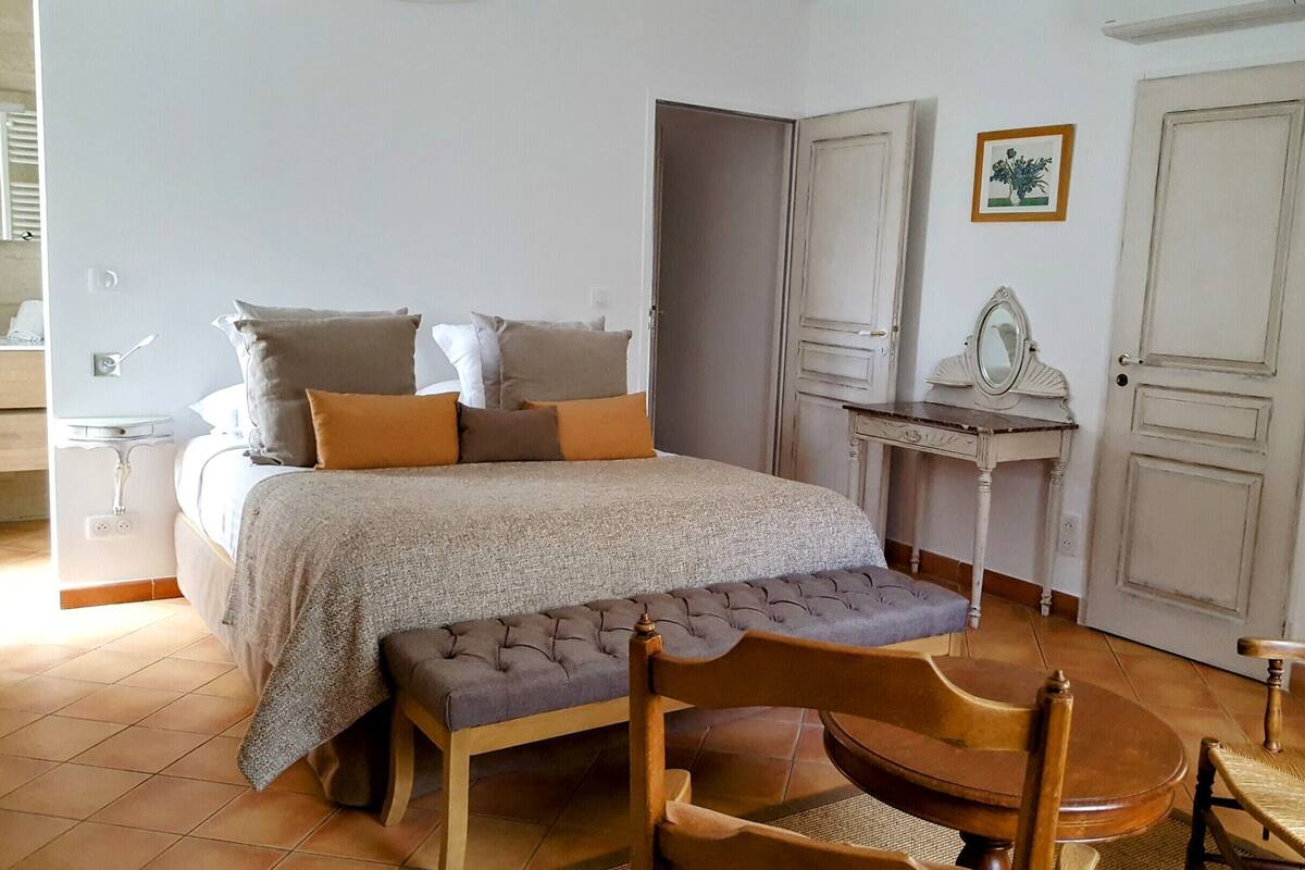 A bedroom with a bed, a bedside table, a chair, and a dresser.