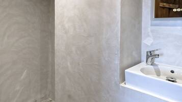 A modern bathroom with a large mirror, a sink, and a shower area.