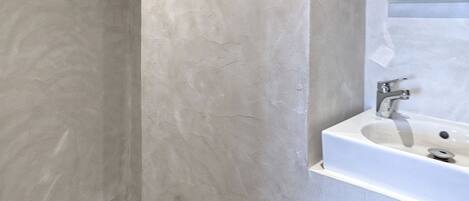 A modern bathroom with a large mirror, a sink, and a shower area.