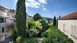 Un patio con edificios, un árbol alto y una montaña al fondo.